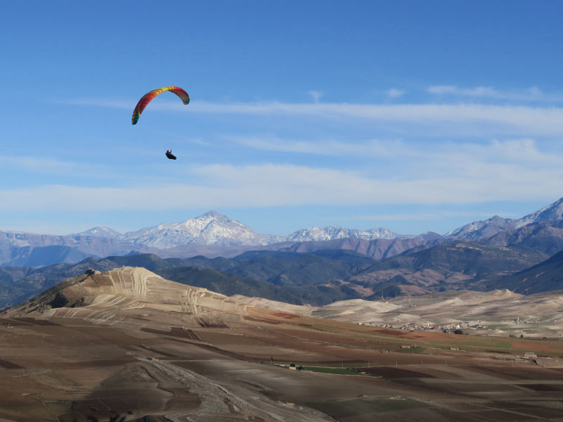 Fred qui vole avec sa BGD Cure au dessus d'Aguergour sur fond du Plateau du Kik et du haut Atlas